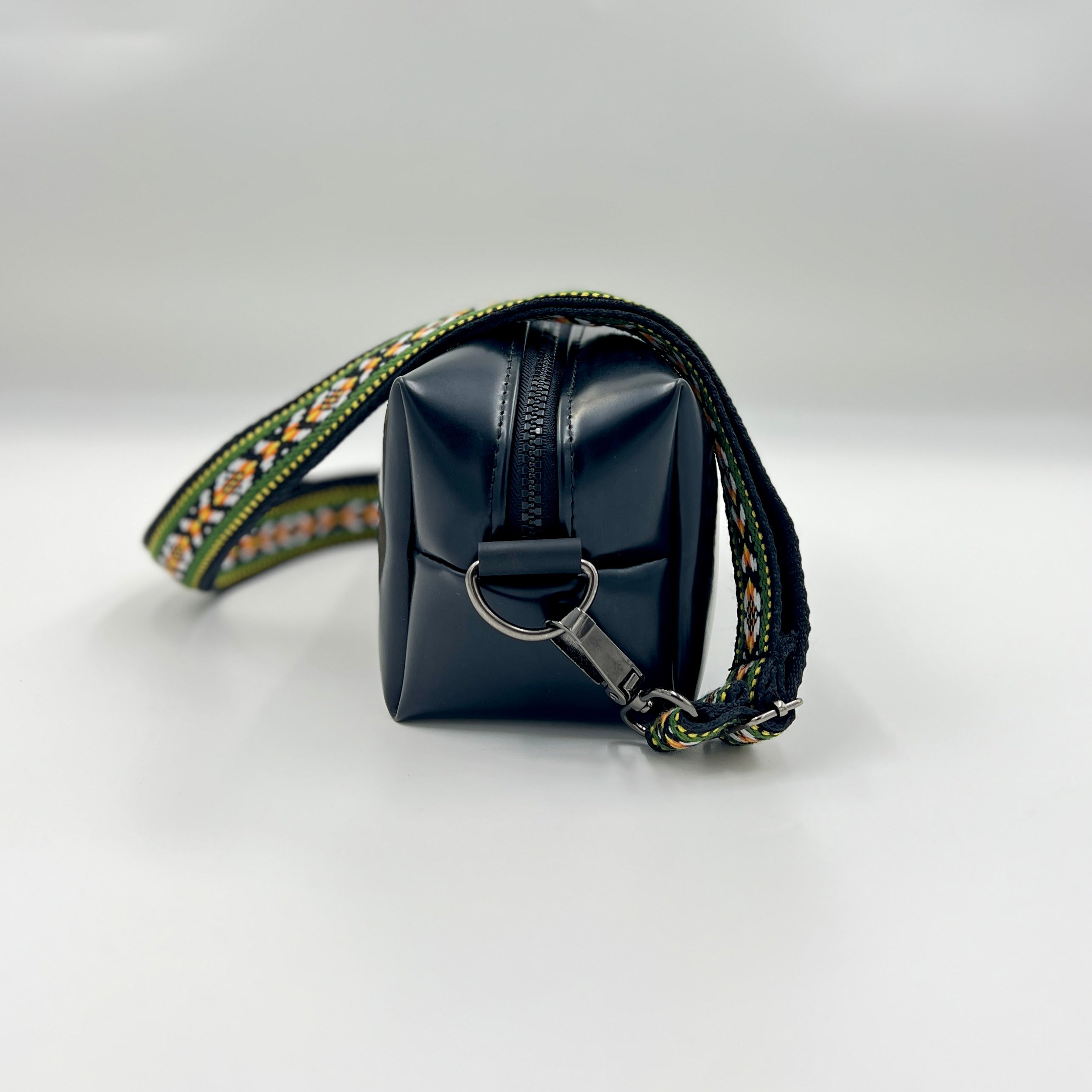 Black square pouch with decorative strap on a white background