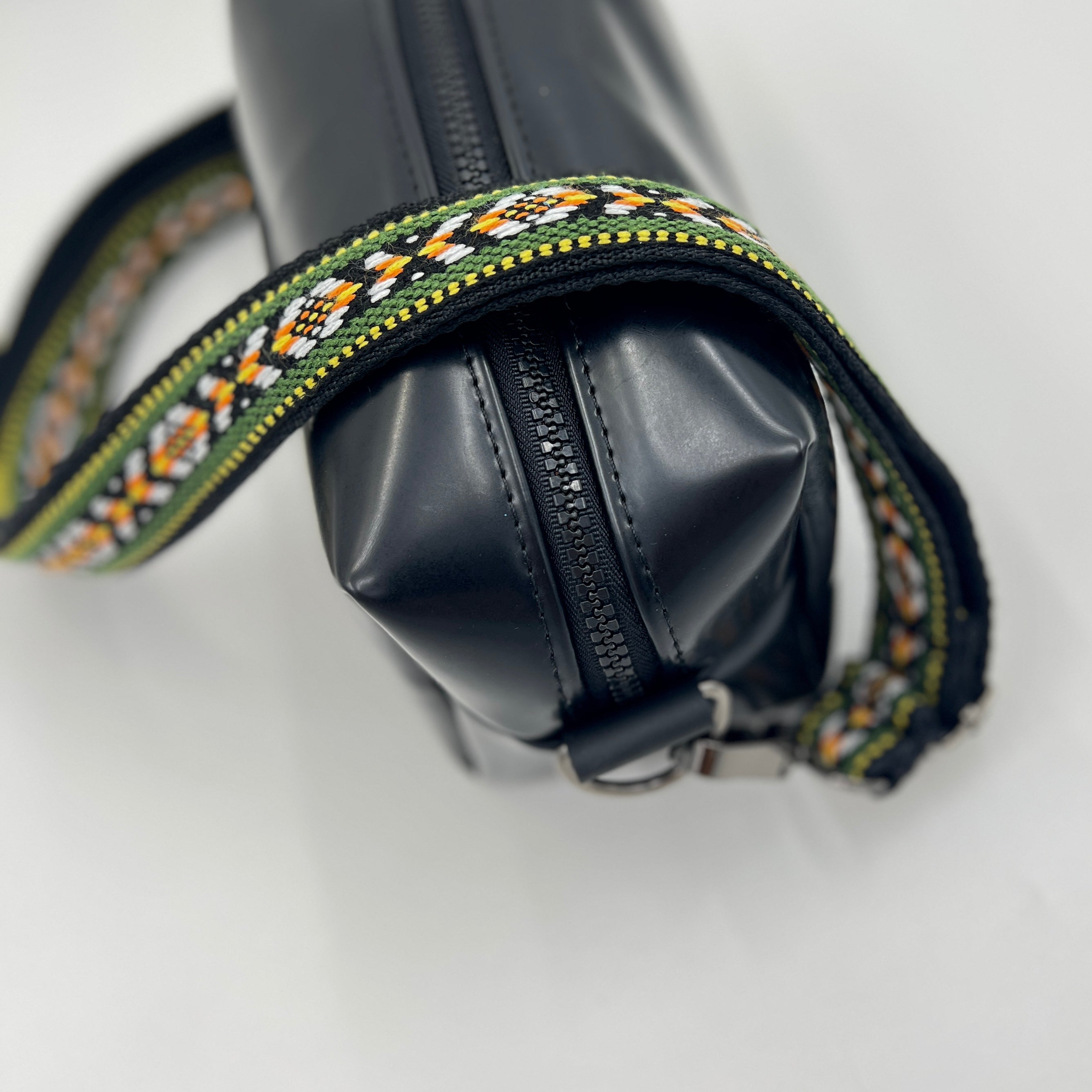 Black bag with a decorative strap on a white background