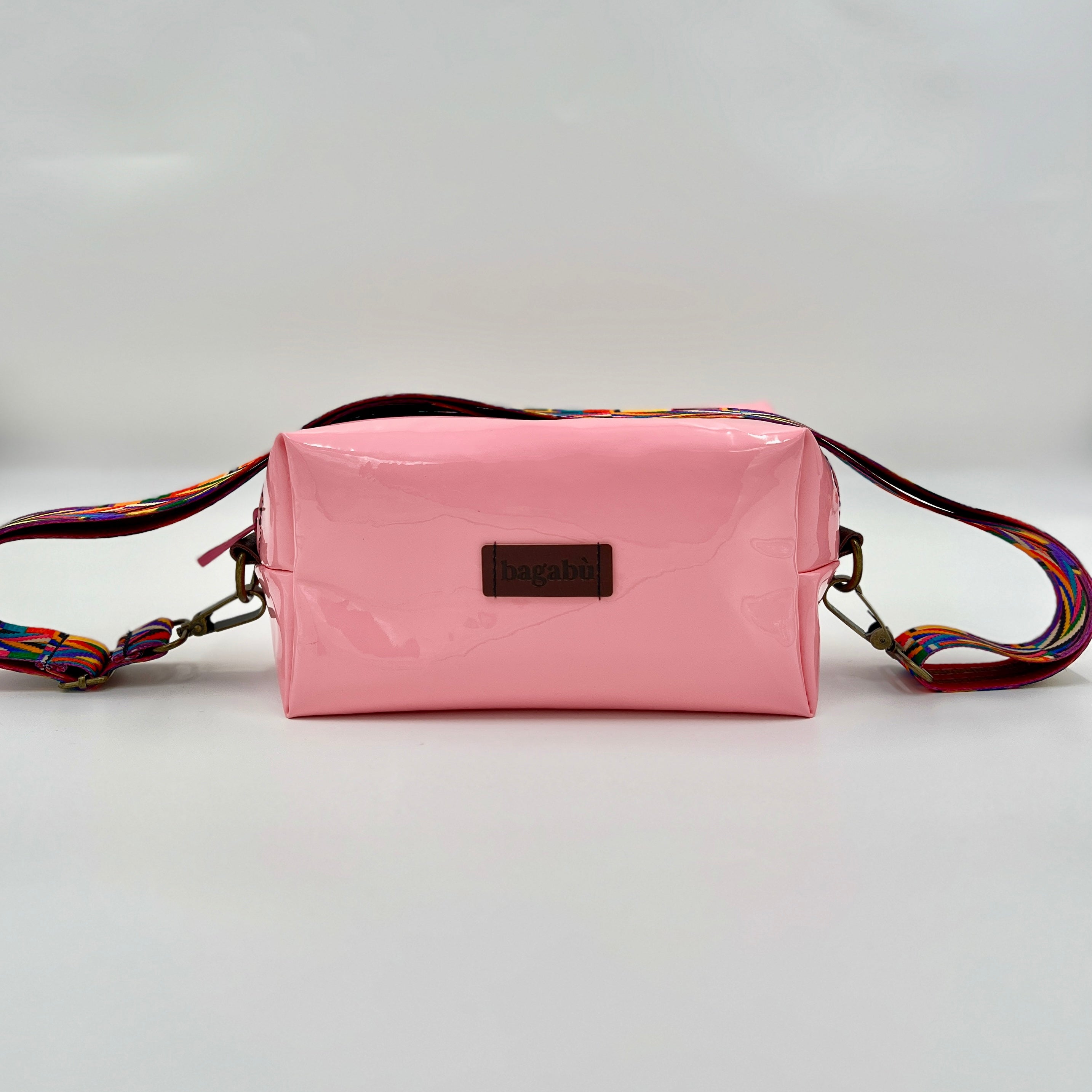 Pink crossbody bag with a colorful strap on a light gray background