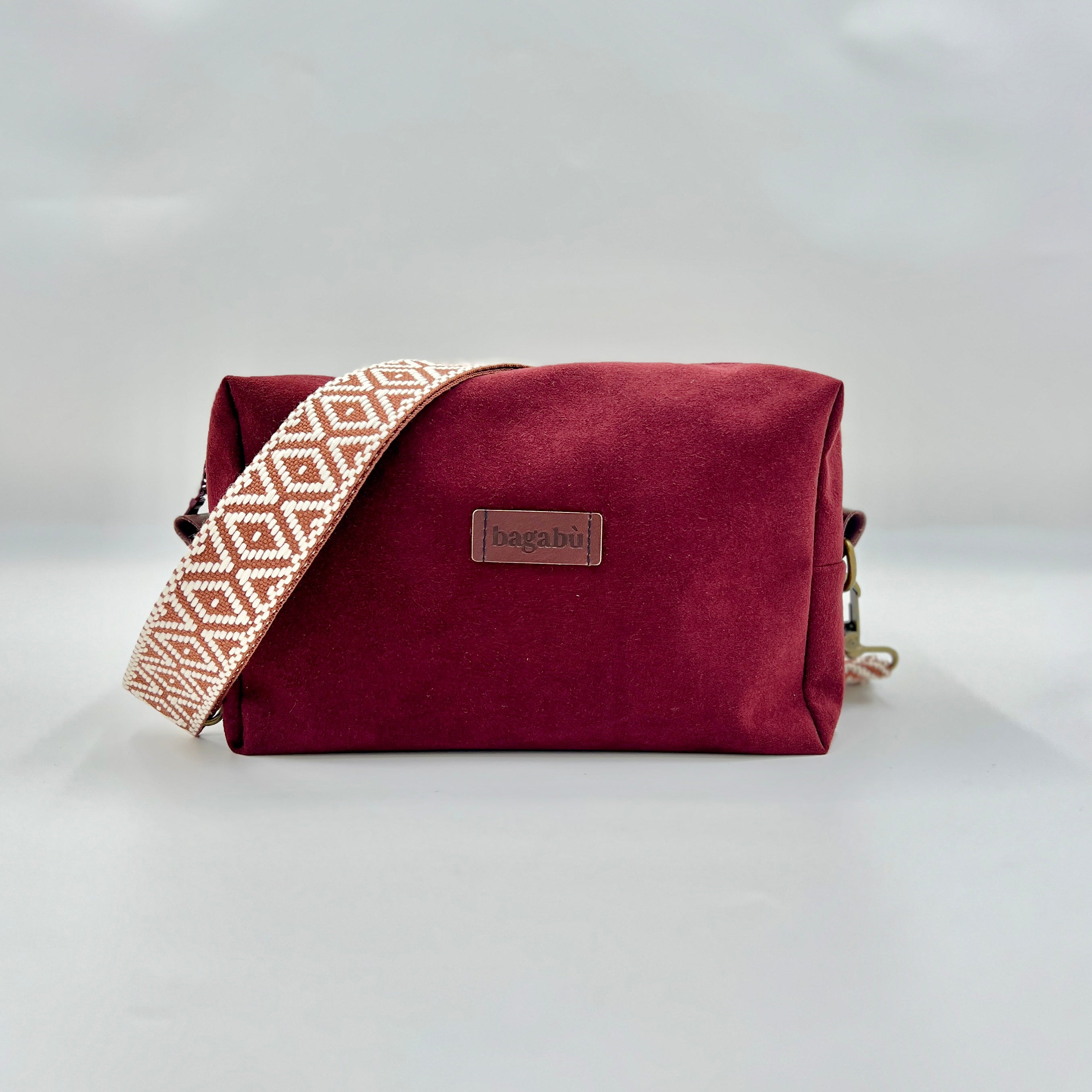 Maroon bag with a patterned strap on a white background