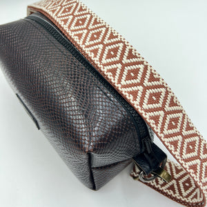 Brown textured pouch with a patterned strap on a white background