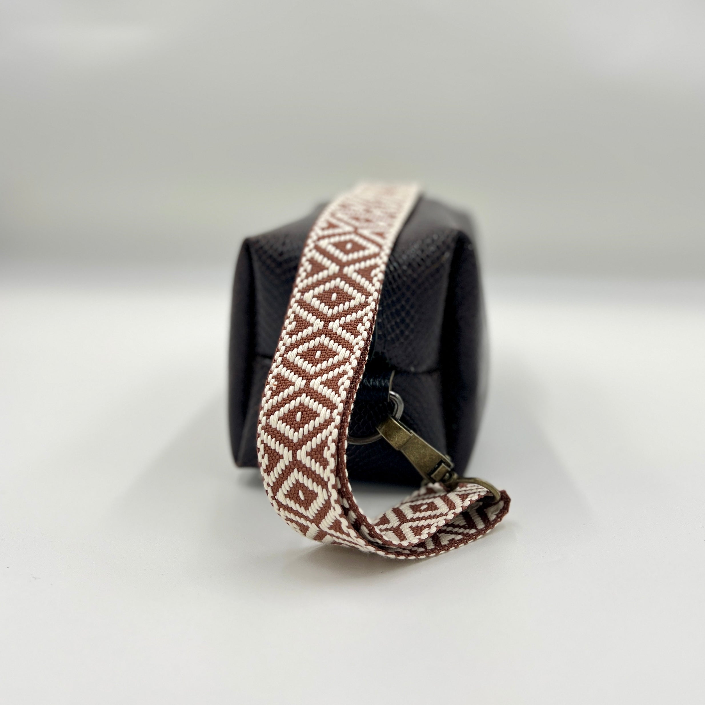 Black bag with a patterned strap on a light gray background