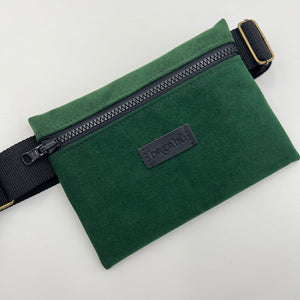 Green waist bag with a visible brand label on a light gray background