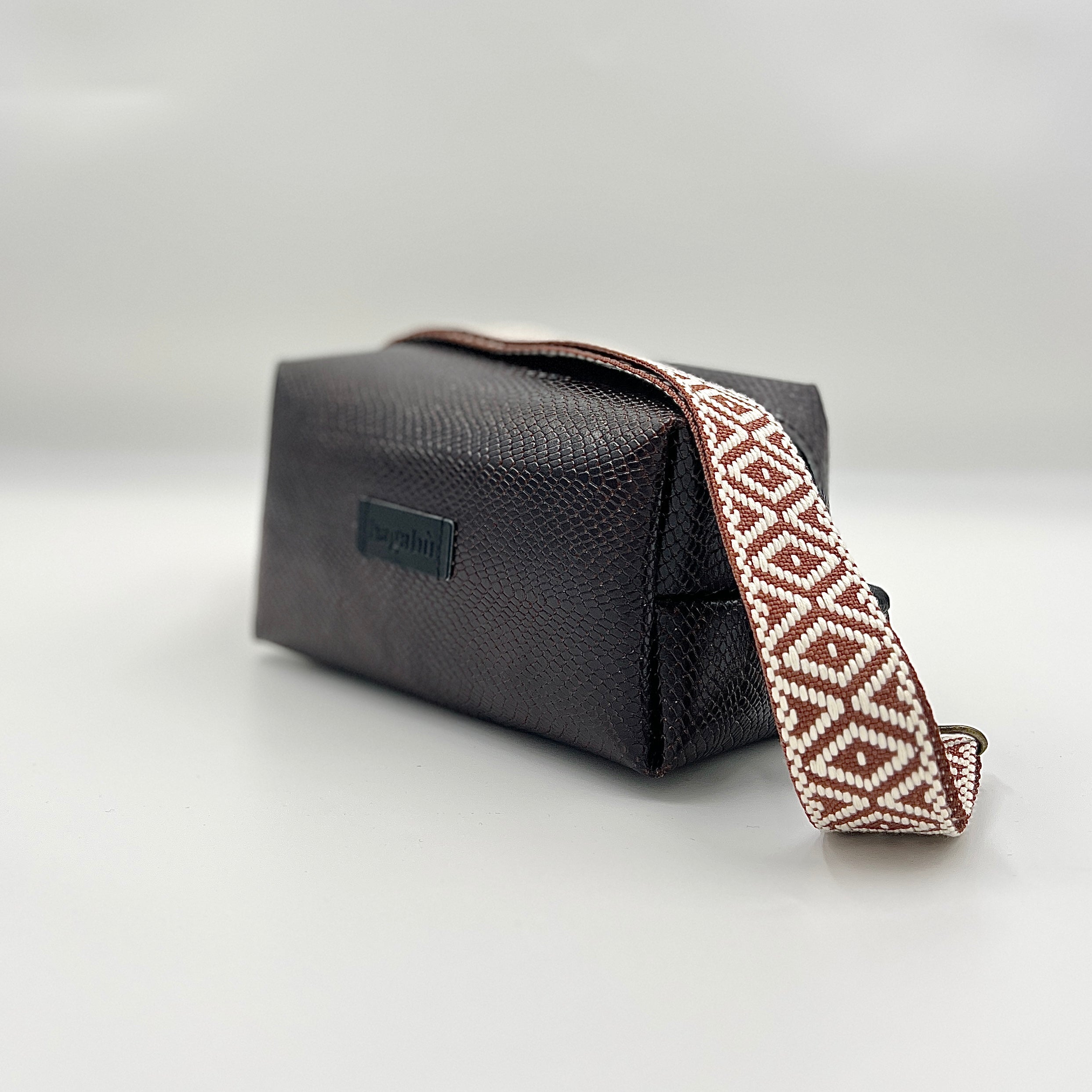 Black leather pouch with a patterned strap on a light gray background