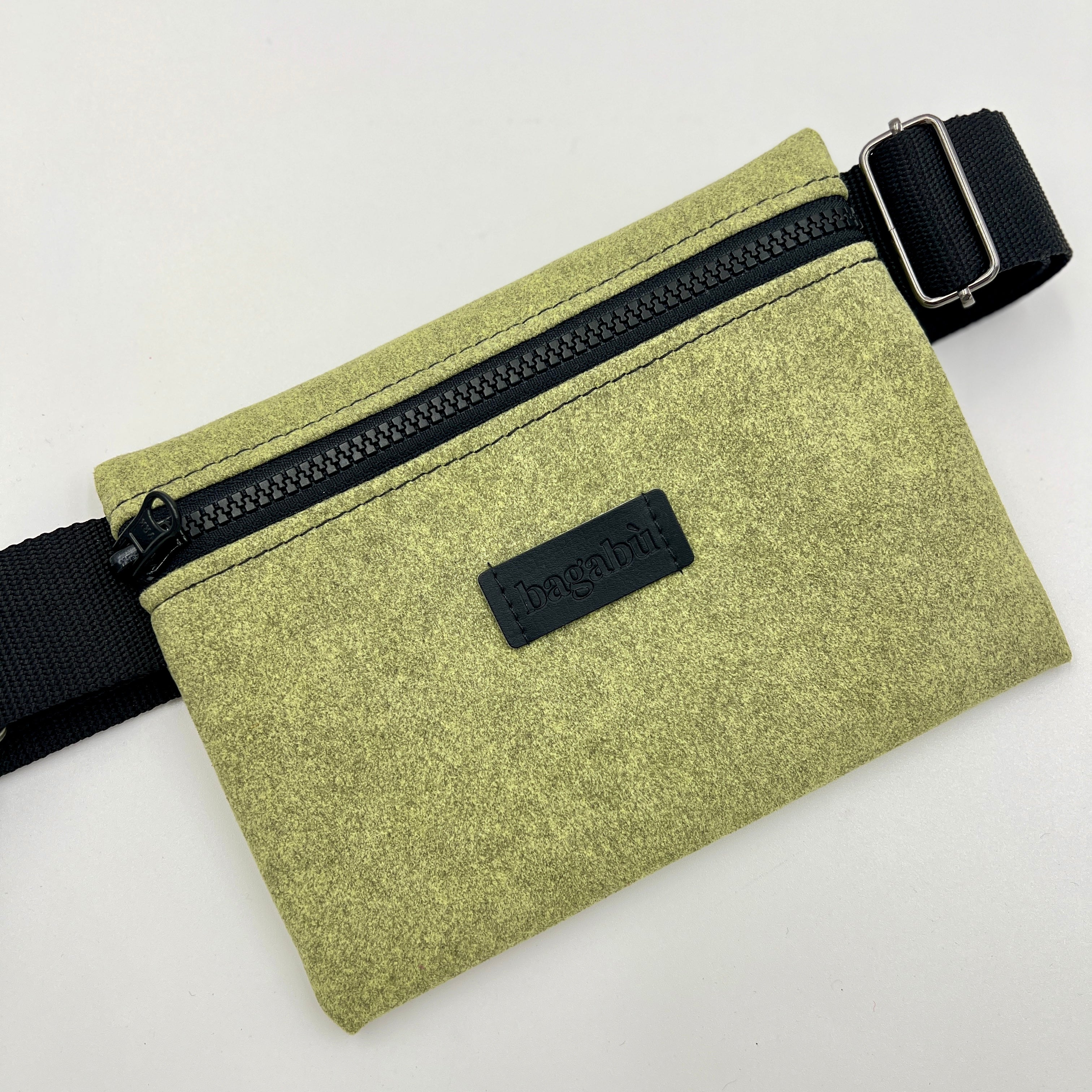 Green waist bag with black zipper and strap on a white background