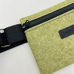 Green waist bag with black zipper and strap on a light gray background