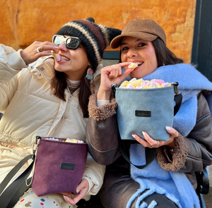 Two women enjoying snacks from bags, one holding a blue bag with a visible brand logo.